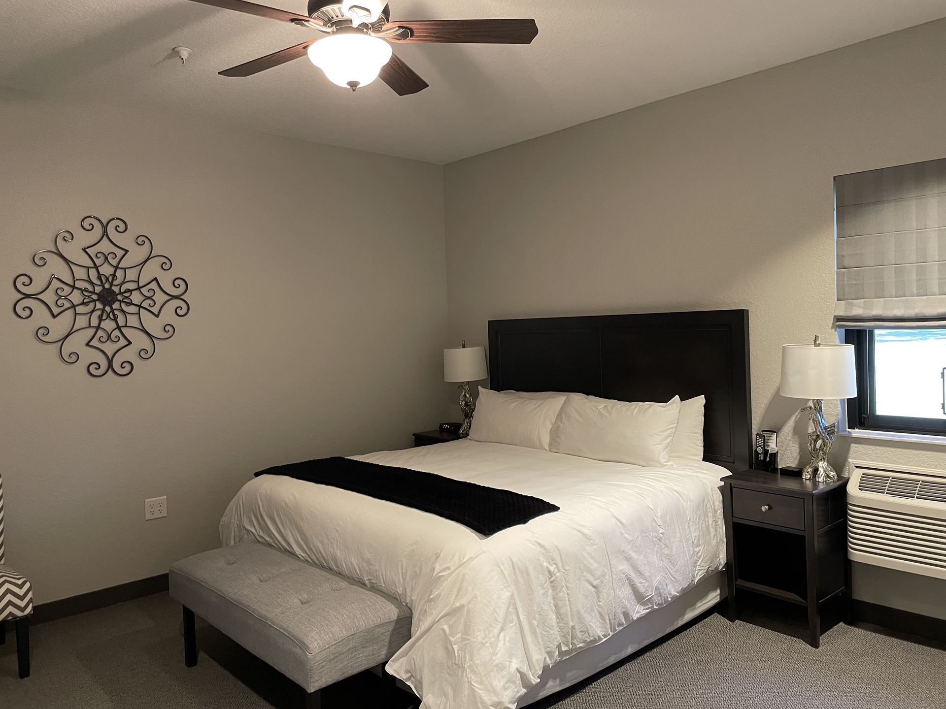 a bed with nightstand and ceiling fan